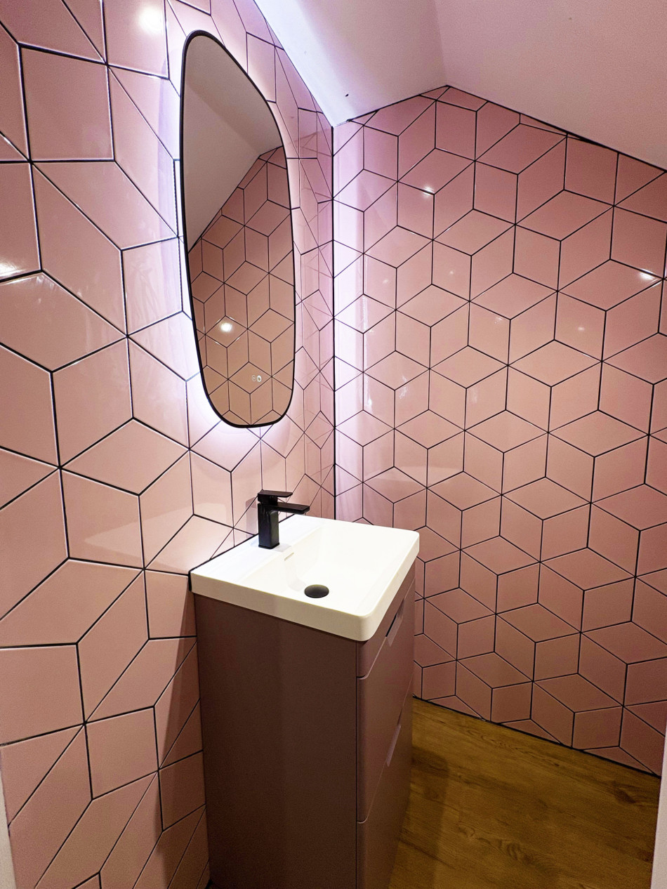 A stylish bathroom adorned with pink tiles and a sleek basin, offering a fresh and inviting look