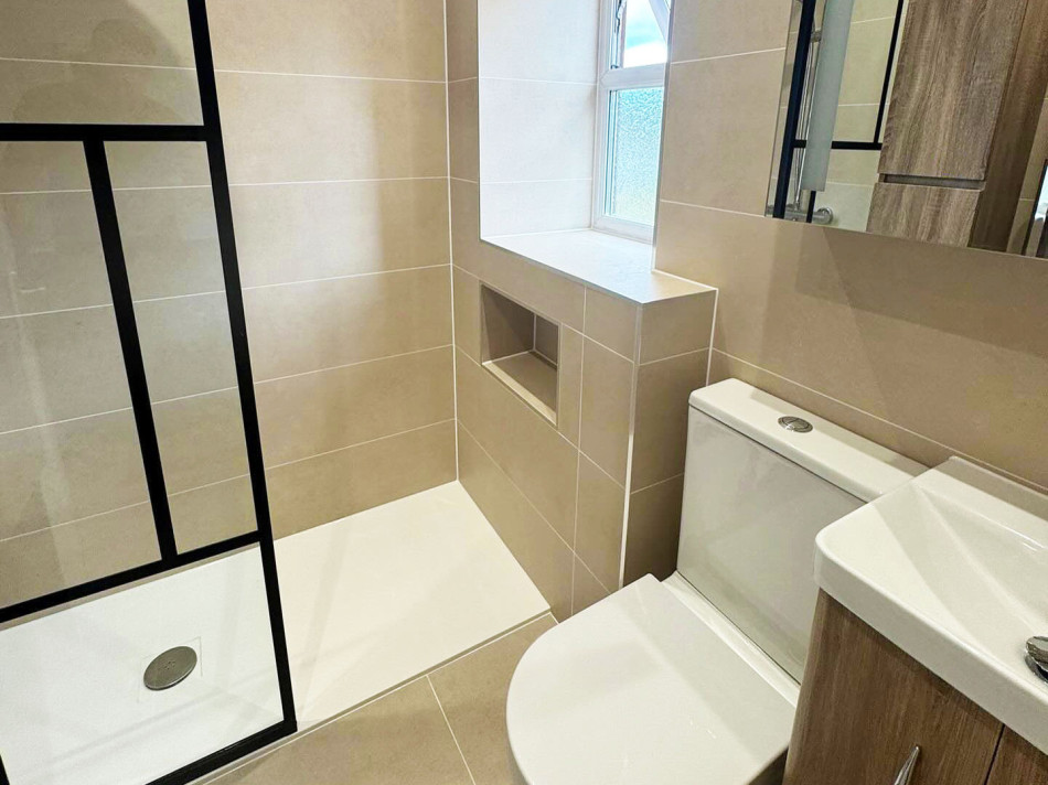 A modern bathroom featuring a toilet, basin, and a spacious shower area