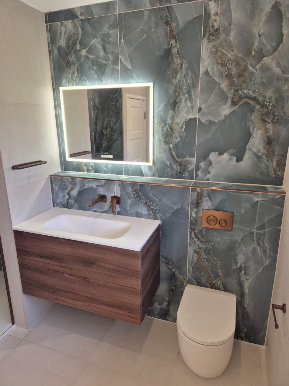 A stylish bathroom featuring a sleek marble wall and a modern wooden vanity unit