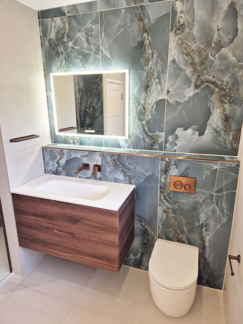 A stylish bathroom featuring a sleek marble wall and a modern wooden vanity unit.