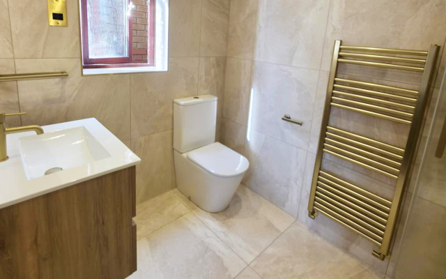 A bathroom featuring a toilet, basin, and a towel rack against a neutral-colored wall