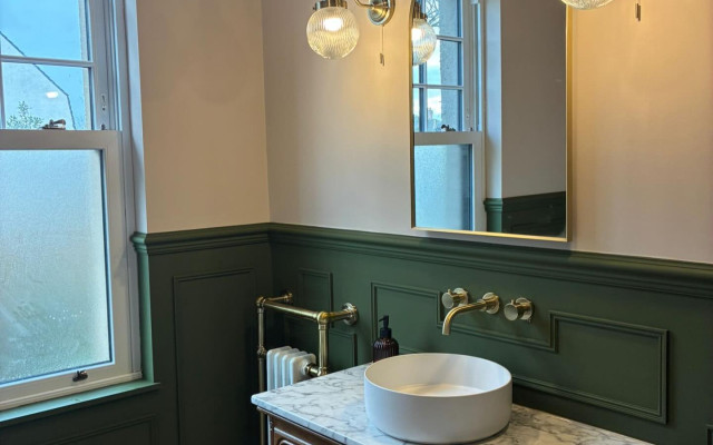 A modern bathroom showcasing green walls complemented by gold trim details