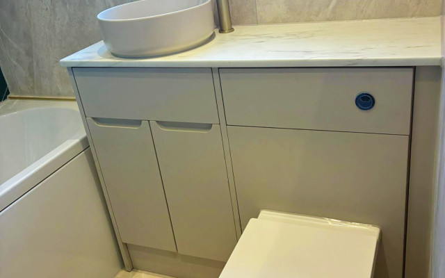 A clean bathroom featuring a toilet, basin, and bath arranged for easy access and comfort
