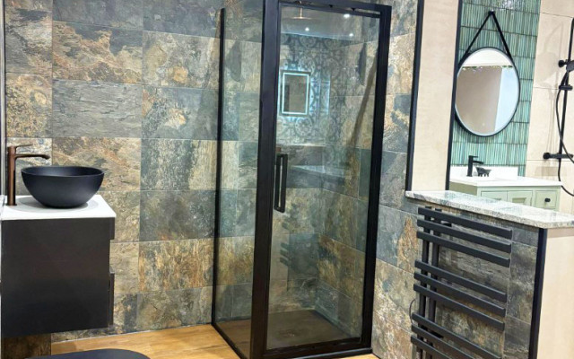 A clean bathroom showroom layout showcasing a shower, basin, and toilet against a light-colored wall