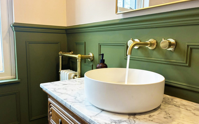 A stylish bathroom with vibrant green walls and an elegant marble basin, enhancing the space's contemporary design