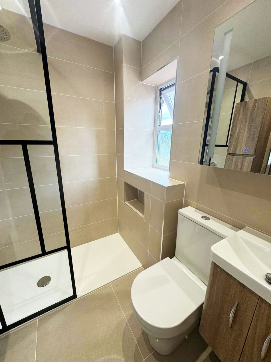 A modern bathroom featuring a toilet, basin, and a spacious shower area