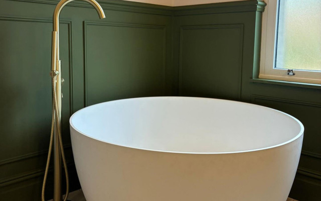 A white bathtub sits in a bathroom with vibrant green walls, creating a fresh and inviting atmosphere