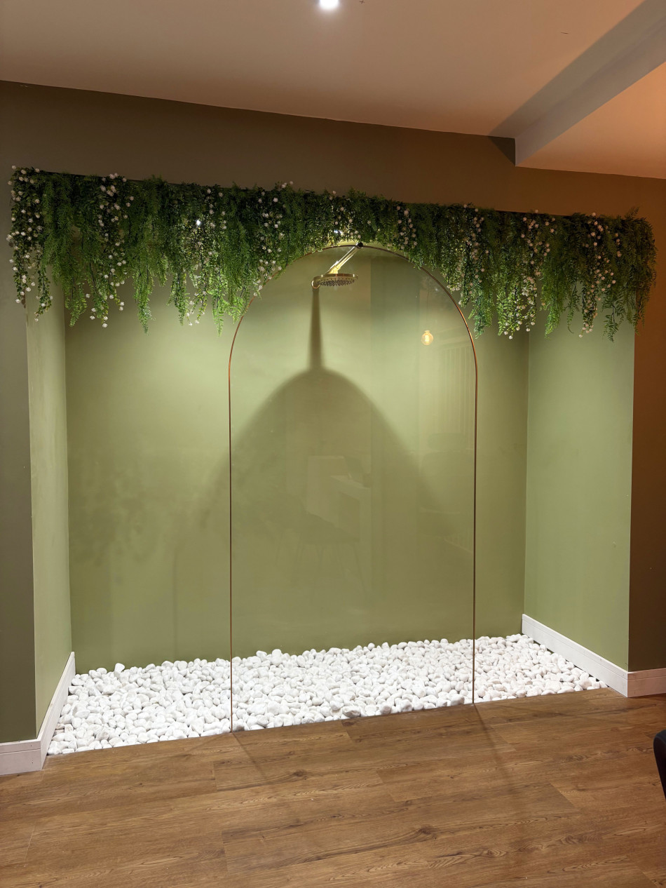 A stylish shower room with a transparent glass wall, complemented by vibrant indoor plants.