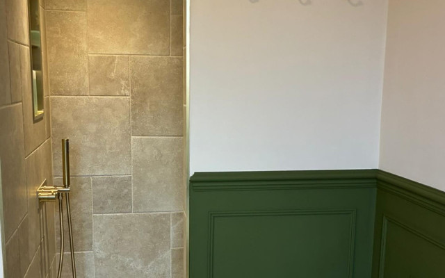 A bathroom featuring green walls and a white toilet, creating a fresh and modern atmosphere