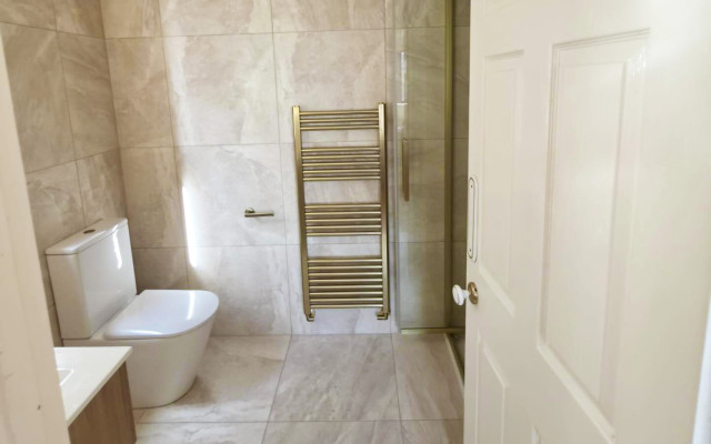 Interior view of a bathroom with a shower, toilet, and a towel rack, showcasing a clean and functional design.