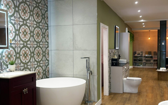 A stylish bathroom showroom with green and white tile walls and a bathtub