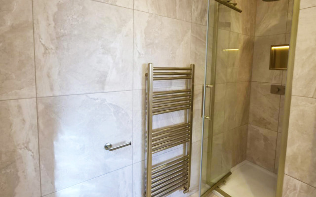 A modern shower with a glass door, featuring a towel rack beside it for convenience